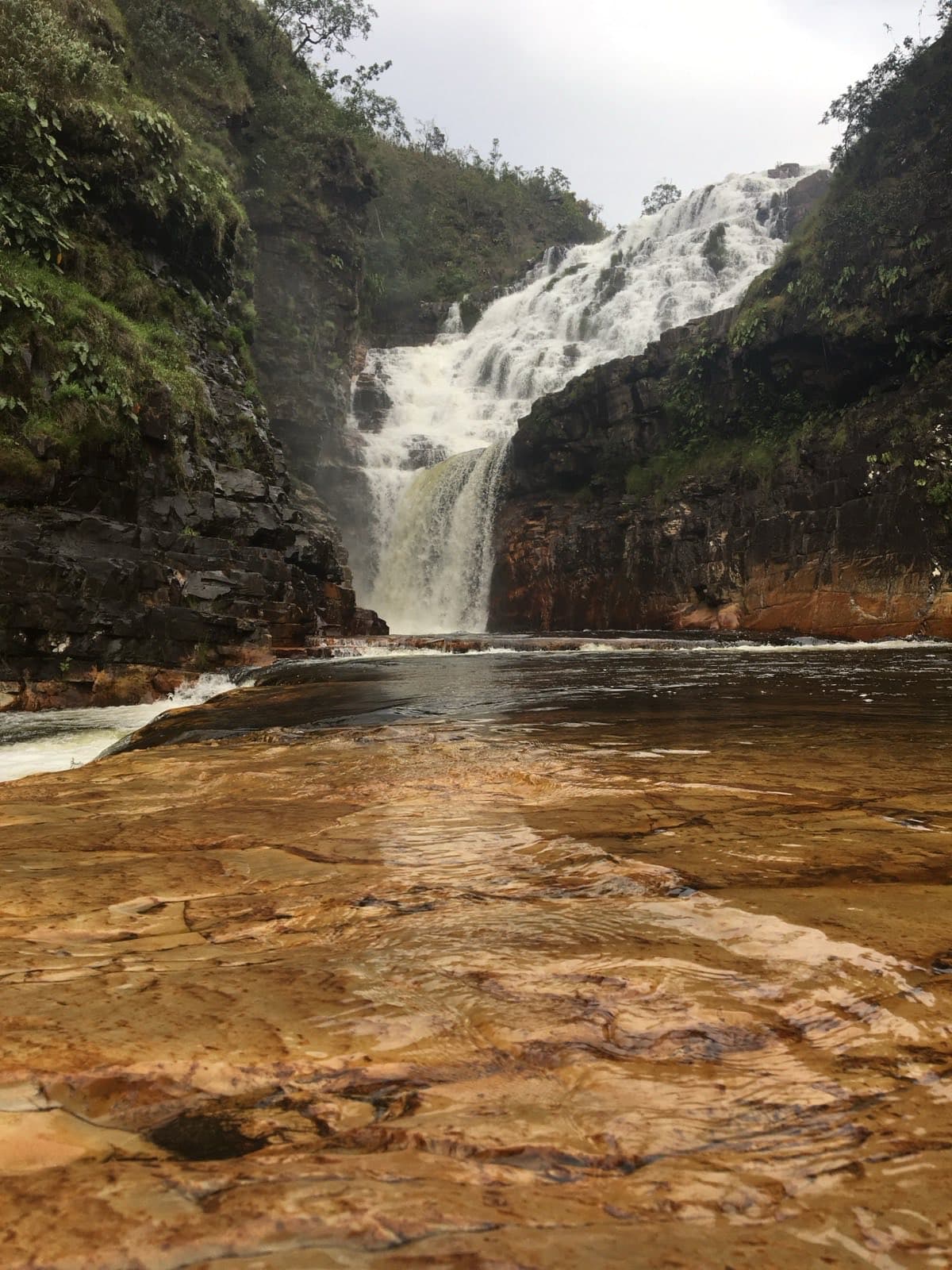 Vista frontal da terceira queda das Cataratas dos Couros, água tranquila sobre a laje de pedra.